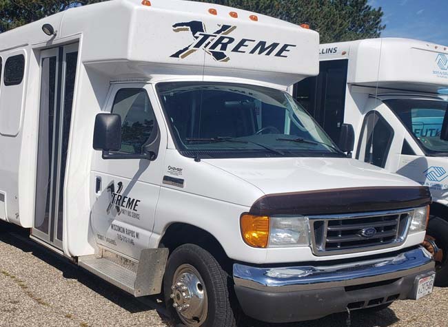 White shuttle van labeled XTREME parked near a Limo Bus, perfect for your Bachelor Party fun.