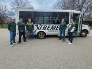 Five men in casual sportswear stand by a white Xtreme Party Bus Service bus, ready for fun.