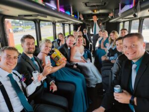 Wedding party celebrating on a Wisconsin Xtreme Party Bus, bride and groom smiling at center.