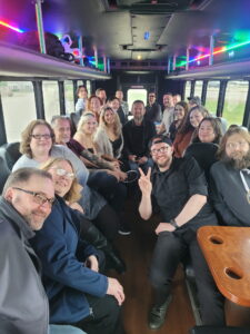 A group of people smiling on an Xtreme Party Bus Service with colorful lights inside.