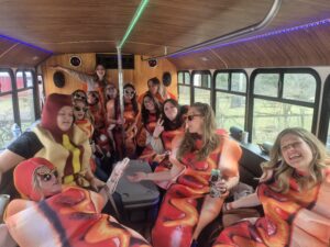 A group in hot dog costumes enjoys drinks and laughter on a Wisconsin bachelor party bus.