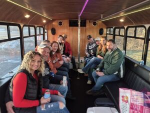 A group enjoys a Wisconsin bachelorette party, smiling on a bus with drinks during their outing.