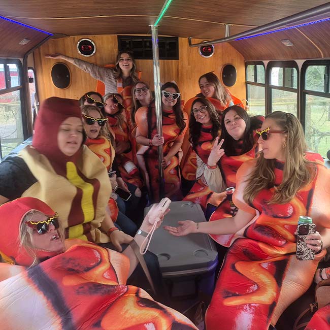 Group of women in hot dog costumes laughing on a Wisconsin Xtreme Party Bus Service party ride.