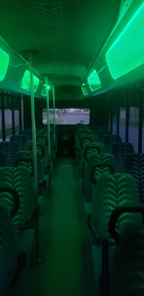 Wisconsin’s Xtreme Party Bus Service: empty limo bus interior aglow with green overhead lights.