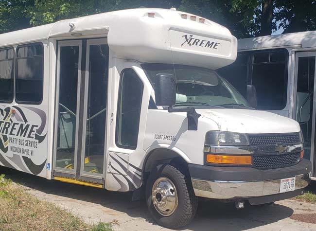 White party bus with Xtreme logo, ideal for a Bachelor Party, parked outdoors on a sunny day.