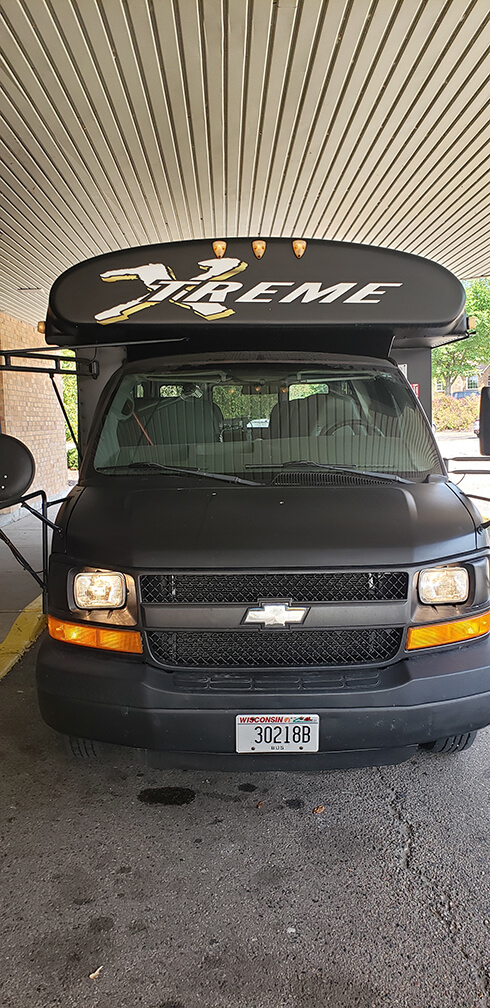 Black Chevrolet van with XTREME, ideal for a Wisconsin bachelorette party, parked under cover.