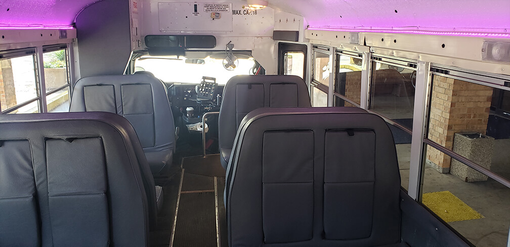 Limo Bus with empty seats, purple lighting, and a view of the driver’s area at the front.