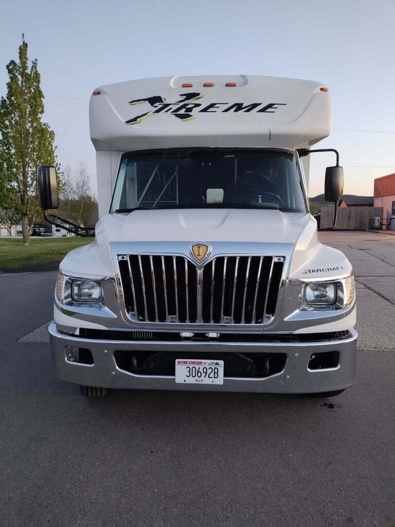 White RV with Xtreme on front, parked street head-on—perfect for a Wisconsin bachelor party.